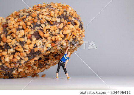 Fitness Woman Struggling Under Giant Donut Concept Fitness Woman Struggling Under Giant Donut Concept 134496411