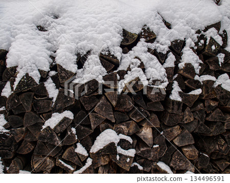 A woodpile. Old black firewood under fluffy snow. A woodpile. Old black firewood under fluffy snow. 134496591