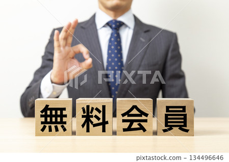一位商人擺出「OK」的姿勢,旁邊立著一塊寫著「免費會員」的牌子。 一位商人擺出「OK」的姿勢,旁邊立著一塊寫著「免費會員」的牌子。 134496646