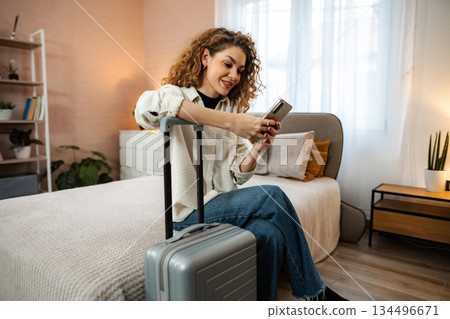 Young woman using smartphone for travel booking in cozy hotel room Young woman using smartphone for travel booking in cozy hotel room 134496671
