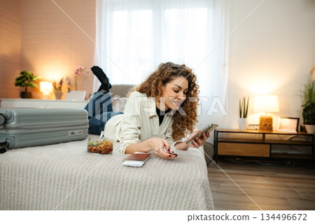 Woman planning trip on phone in hotel room 134496672