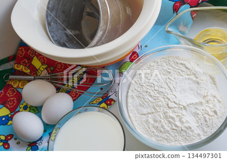 raw ingredients for pancakes are laid out on a multi-colored tablecloth raw ingredients for pancakes are laid out on a multi-colored tablecloth 134497301
