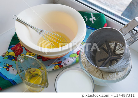 raw ingredients for pancakes are laid out on a multi-colored tablecloth and white background raw ingredients for pancakes are laid out on a multi-colored tablecloth and white background 134497311