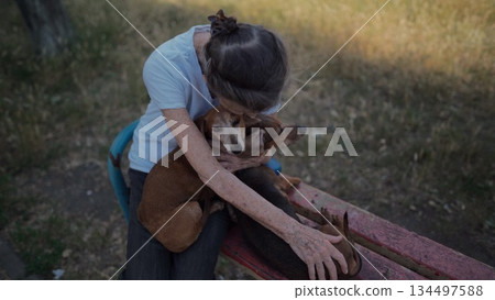 Animal theme is a lonely old woman best friend. Caucasian 90 years old senior female is happy to spend time with her pet small dachshund dog, holding her in her arms, hugging hugs and kisses outdoor Animal theme is a lonely old woman best friend. Caucasian 90 years old senior female is happy to spend time with her pet small dachshund dog, holding her in her arms, hugging hugs and kisses outdoor 134497588