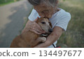 Animal theme is a lonely old woman best friend. Caucasian 90 years old senior female is happy to spend time with her pet small dachshund dog, holding her in her arms, hugging hugs and kisses outdoor 134497677