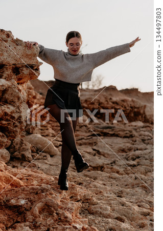 Woman Rocks Outdoors Pose: Joyful cliffside balancing act; autumnal landscape photo shoot. 134497803
