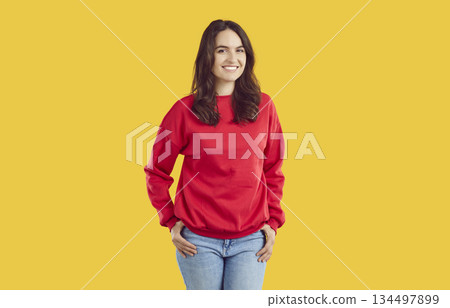 Smiling young woman standing with her hands on hips 134497899