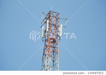 Telecommunication tower with multiple antennas and transmitters standing against a clear blue sky 134497923
