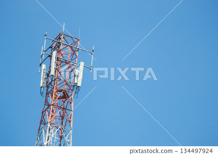 Telecommunication tower with multiple antennas and transmitters standing against a clear blue sky 134497924