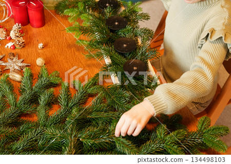 Child arranging advent wreath with candles and pine branches Child arranging advent wreath with candles and pine branches 134498103
