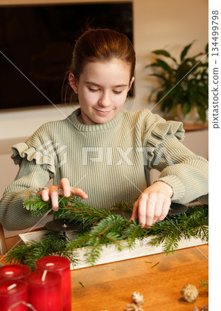 Girl preparing Advent wreath with fir branches at home 134499798