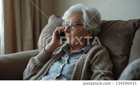 A senior Western woman listening to a conversation on her cell phone with a serious expression A senior Western woman listening to a conversation on her cell phone with a serious expression 134500435