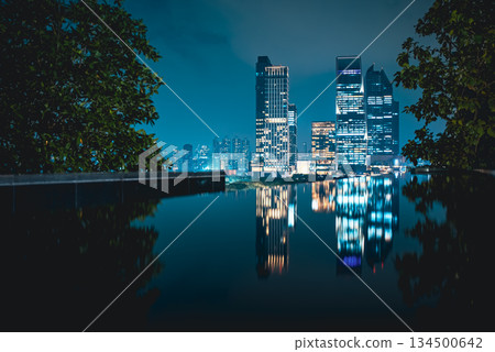 illuminated big city skyline at night with mirrored water reflection, modern high-rise skyscrapers at urban dusk, downtown mirroring on calm lake or pond, Bangkok Thailand illuminated big city skyline at night with mirrored water reflection, modern high-rise skyscrapers at urban dusk, downtown mirroring on calm lake or pond, Bangkok Thailand 134500642