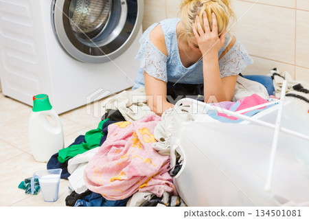 Unhappy girl sorting dirty clothes laundry. Unhappy girl sorting dirty clothes laundry. 134501081