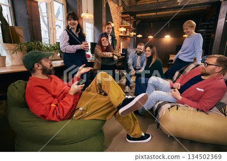 Group of coworkers relaxing and talking in modern workspace. Group of coworkers relaxing and talking in modern workspace. 134502369