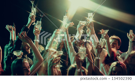 Hands holding sparkling drinks raised in Christmas celebration Hands holding sparkling drinks raised in Christmas celebration 134502390