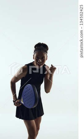 Emotional female padel player celebrating winning point on white background. Emotional female padel player celebrating winning point on white background. 134502425