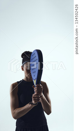 Female padel player hitting forehand shot in motion on white background. 134502426