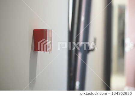 Fire alarm on wall in indoor hallway setting Fire alarm on wall in indoor hallway setting 134502930