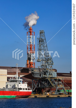 Large crane works on Steel factory at Industrial port. Cargo transportation and activity at modern shipping terminal. Large crane works on Steel factory at Industrial port. Cargo transportation and activity at modern shipping terminal. 134503487