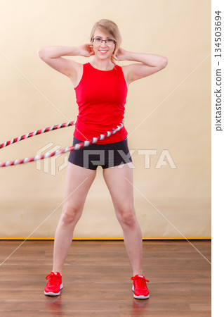 Fit woman with hula hoop doing exercise 134503694