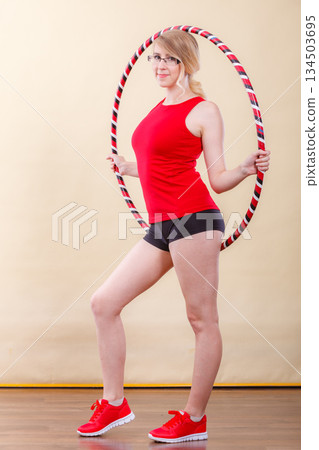 Fit woman with hula hoop doing exercise 134503695
