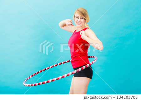 Fit woman with hula hoop doing exercise 134503703