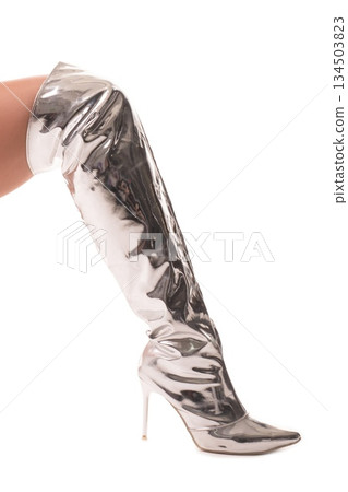 Leg wears shiny silver thigh high stiletto boot on white background for fashion 134503823