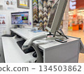 A desk with a computer monitor, keyboard, and barcode scanner against shelves with pictures, perfect for home office setups, inventory management themes, and organized workspace photography. 134503862