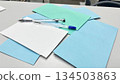 A white table with colored sheets of paper and a pen, suitable for creative brainstorming, note-taking concepts, and minimalist stationery photography. 134503863