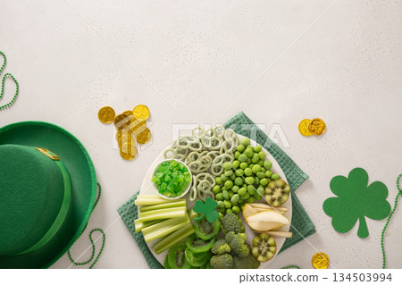 Assorted green snacks with fruits, vegetables and shamrock decor for St Patrick's Day festive celebration. Assorted green snacks with fruits, vegetables and shamrock decor for St Patrick's Day festive celebration. 134503994