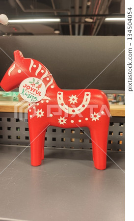 Red wooden Dala horse figurine with white folk patterns displayed on a shop counter. The image represents Scandinavian tradition, handmade craft, and festive Christmas decor concept 134504054