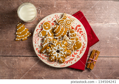 Holiday background. Christmas gingerbread cookies in different shapes in a plate Holiday background. Christmas gingerbread cookies in different shapes in a plate 134504241