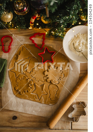 Holiday background. Uncooked raw Christmas gingerbread cookies with cookie cutters on a table, top view, flat lay 134504249