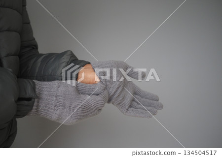 Hands putting on gray gloves in indoor setting Hands putting on gray gloves in indoor setting 134504517