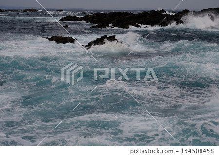 Landscape photo of waves crashing against rocks in strong winds 134508458