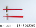 Ceramic chopstick rest and red chopsticks on a white background 134508595