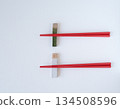 Ceramic chopstick rest and red chopsticks on a white background 134508596