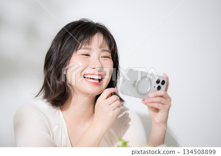 Happy and fun looking at smartphone Close-up of a cute young woman smiling while watching a video on her smartphone 134508899