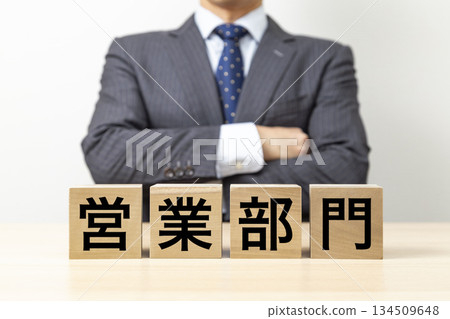 A businessman with his arms folded and a block that reads "Sales Department" A businessman with his arms folded and a block that reads "Sales Department" 134509648