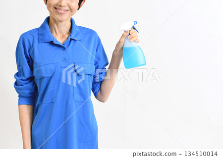 Middle-aged Asian woman in work clothes holding cleaning spray 134510014