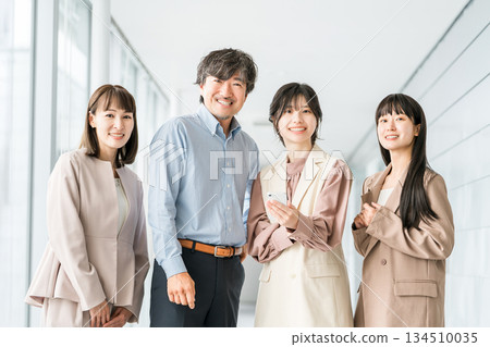 辦公室走廊裡,一對商務人士手持智慧型手機。 辦公室走廊裡,一對商務人士手持智慧型手機。 134510035