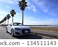 Driving along the seaside in a white sports car 134511143