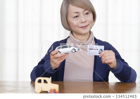 A senior woman thinking about returning her driver's license in the living room A senior woman thinking about returning her driver's license in the living room 134512483