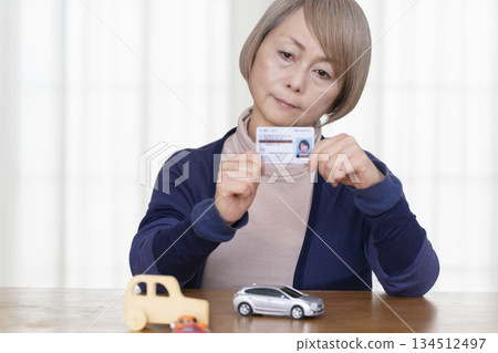A senior woman thinking about returning her driver's license in the living room A senior woman thinking about returning her driver's license in the living room 134512497