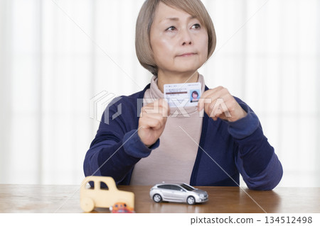 A senior woman thinking about returning her driver's license in the living room 134512498