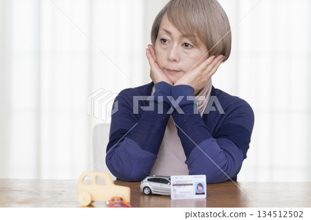 A senior woman thinking about returning her driver's license in the living room A senior woman thinking about returning her driver's license in the living room 134512502