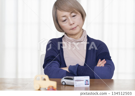 A senior woman thinking about returning her driver's license in the living room A senior woman thinking about returning her driver's license in the living room 134512503