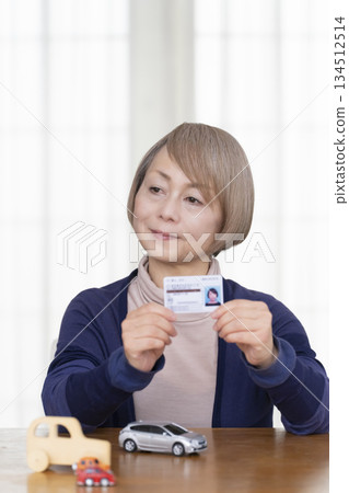 一位老婦人在客廳考慮是否要歸還她的駕照。 一位老婦人在客廳考慮是否要歸還她的駕照。 134512514
