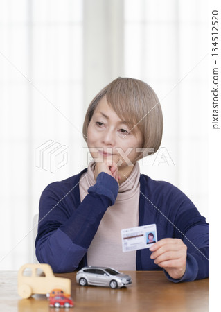 A senior woman thinking about returning her driver's license in the living room A senior woman thinking about returning her driver's license in the living room 134512520